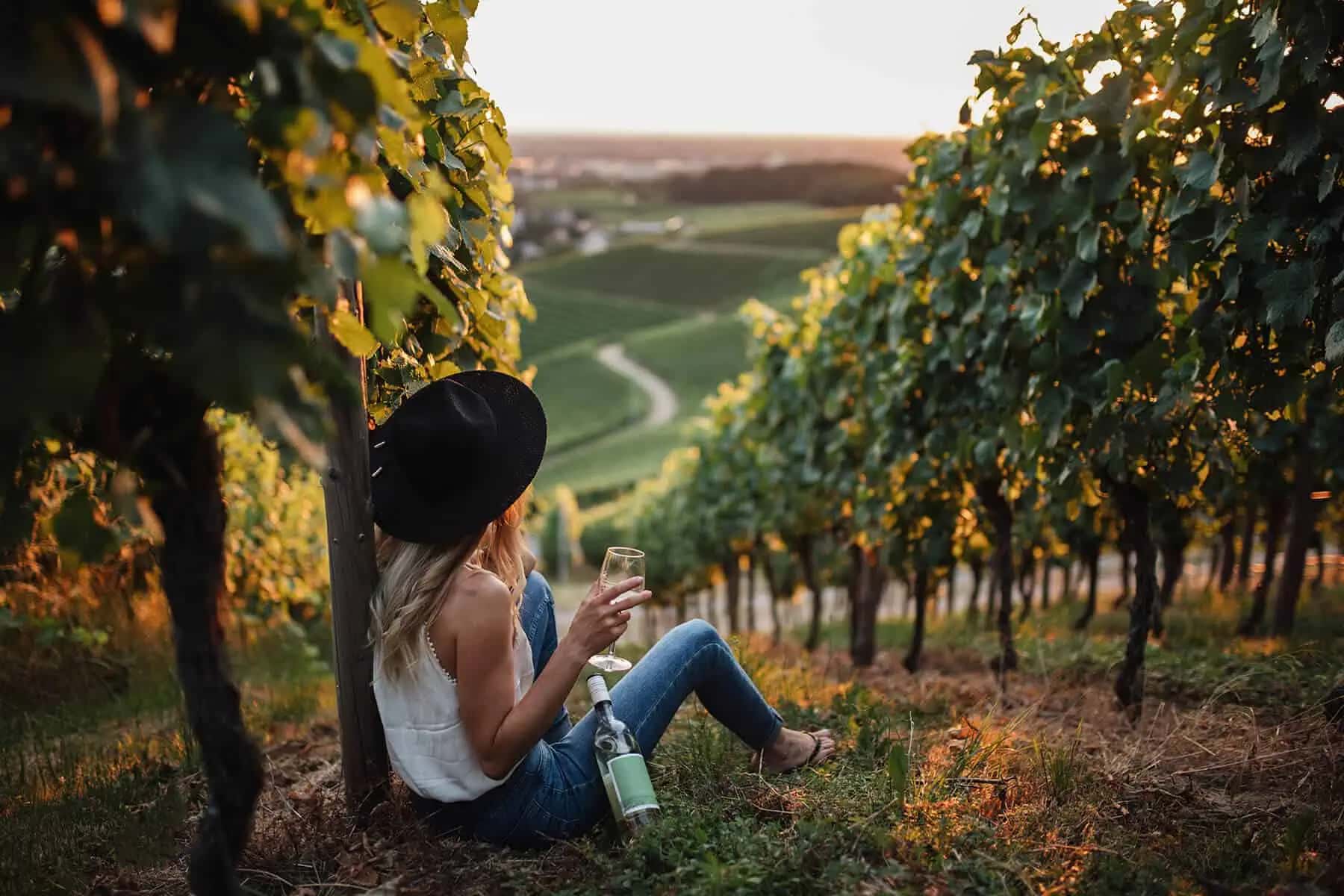 Kvinna med ett glas vitt vin i en vingård